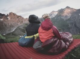 a couple of people sitting on top of a red blanket
