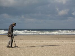 man in black jacket and black pants holding black dslr camera on beach during daytime