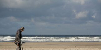 man in black jacket and black pants holding black dslr camera on beach during daytime